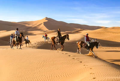 Horseback riders in the Sahara following the trail guide