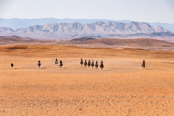 Group of riders cantering against the backdrop of the Namib