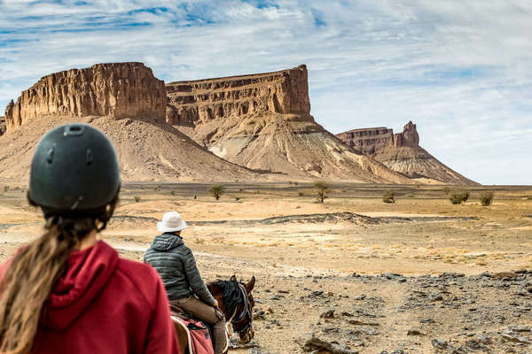 Riders riding out towards mountains in the Sahara