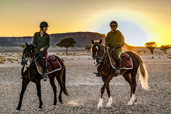 Two riders at sunset in the Sahara