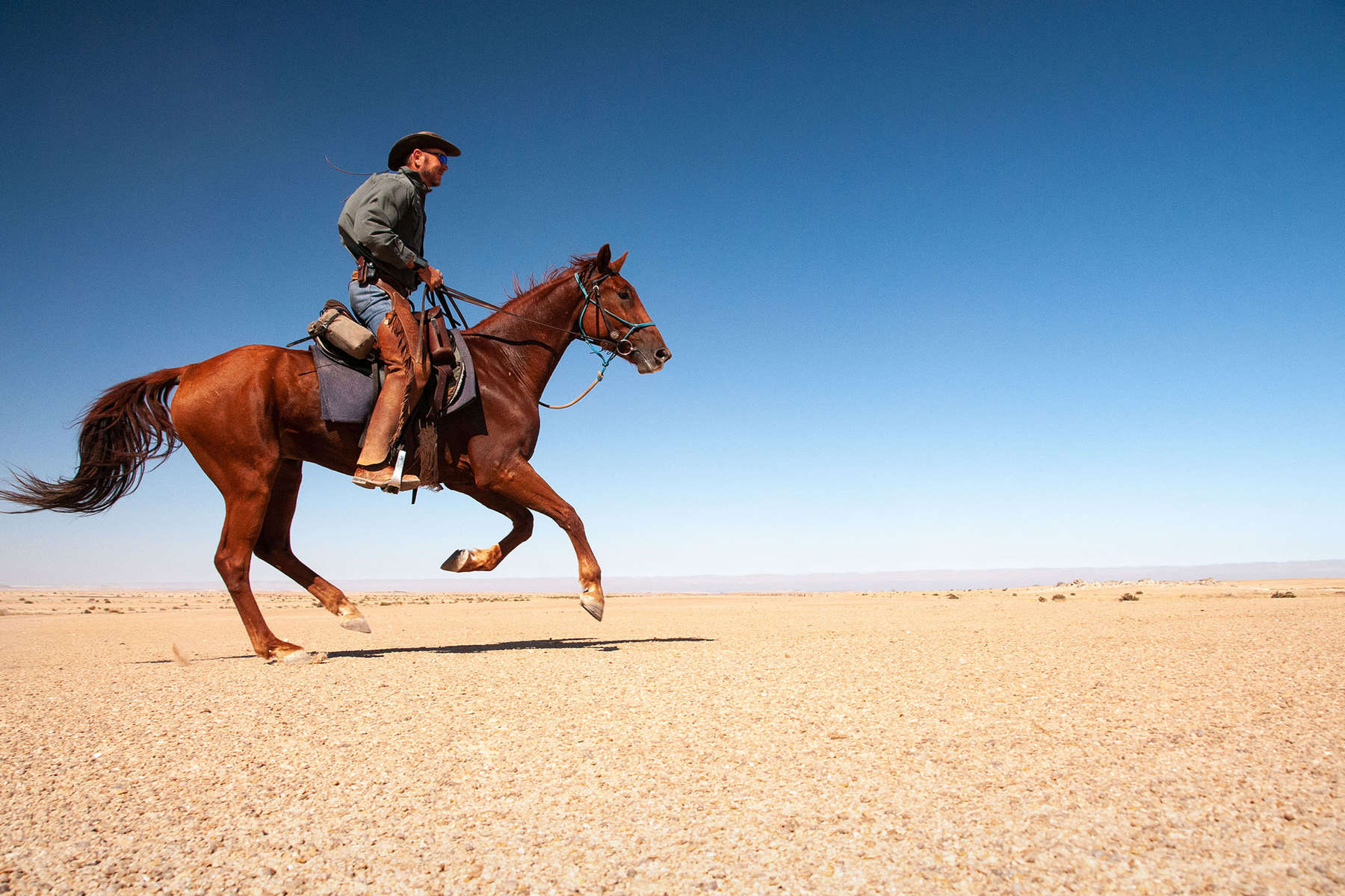 Andrew Gillies riding a horse in the Namib desert