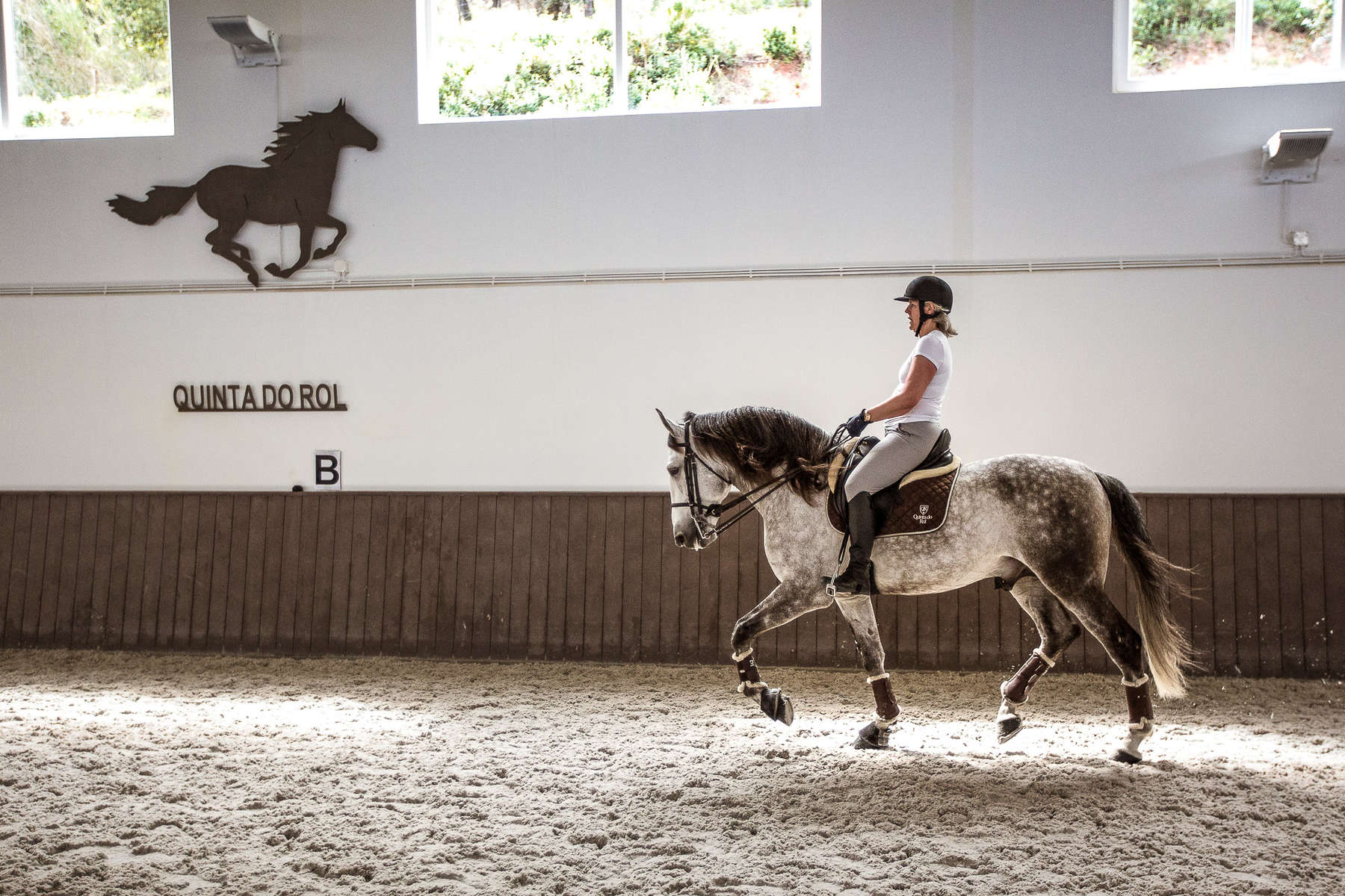 Dressage rider riding a Lusitano horse in the indoor arena at Quinta do Rol