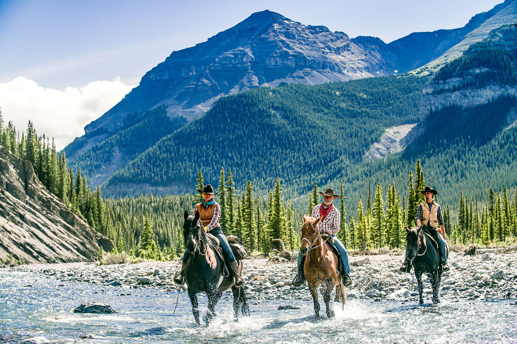 Riders in the river with a spectacular mountainous backdrop