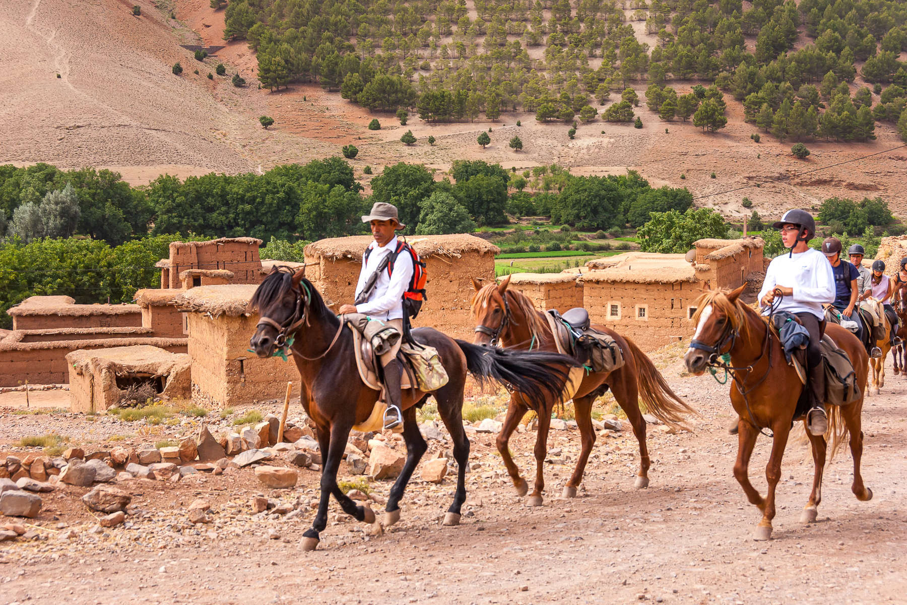 Riders riding across a traditional village in Morocco