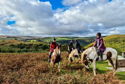 Group of riders enjoying a trail riding holiday in Exmoor, riding over hills