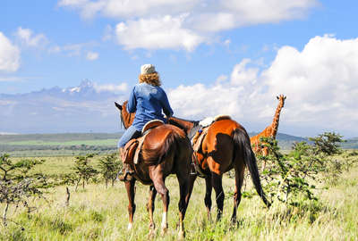 Rider at Borana Lodge and Conservancy watching giraffe on horseback