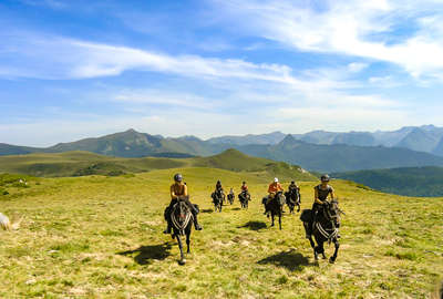 Riders cantering in a valley on a trail riding holiday