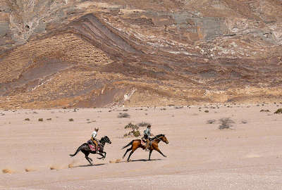 Riders galloping in a desert in Namibia