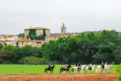 Riders passing a Spanish village on horseback