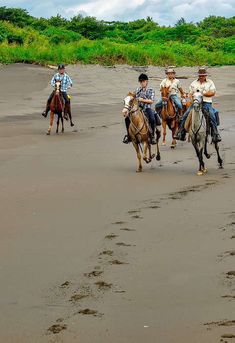You will experience exhilarating beach rides that call for lively canters Group of riders cantering in a beach in Costa Rica
