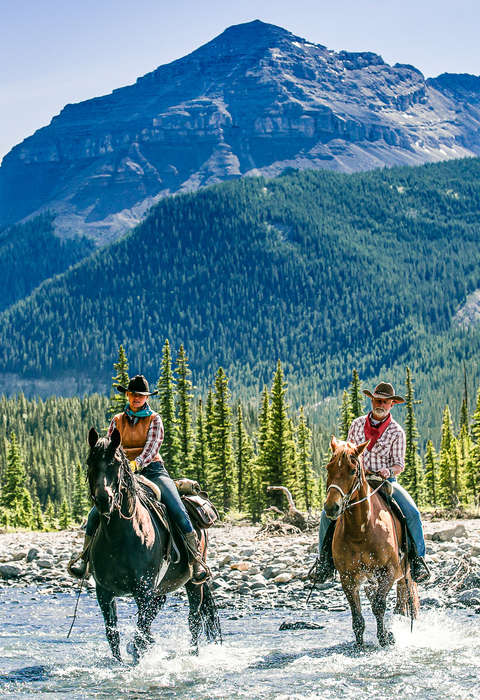 Riders in the river with a spectacular mountainous backdrop