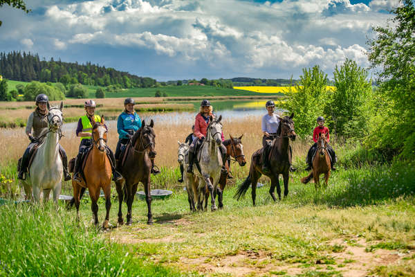 A group of international riders riding by a lake in Poland