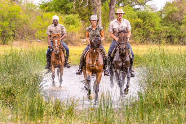 A group of rider cantering in the plaines in Botswana