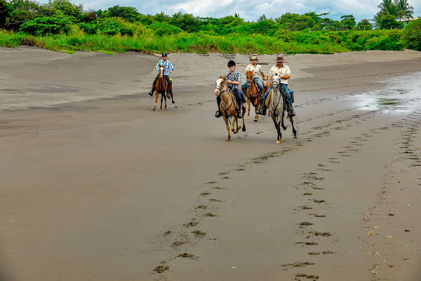 Group of riders cantering in a beach in Costa Rica