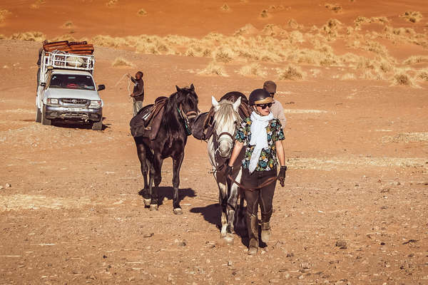 Horse back rider leading her horse ahead of  a trail ride
