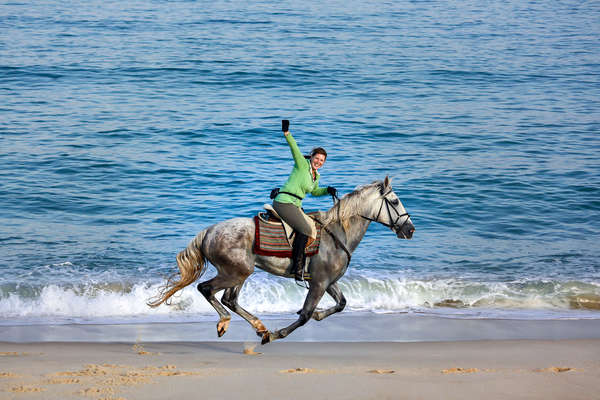 Horseback rider having fun on the beach with an exhilarating gallop