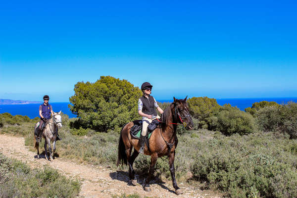 Horseback riders on a coastal trail ride in Spain