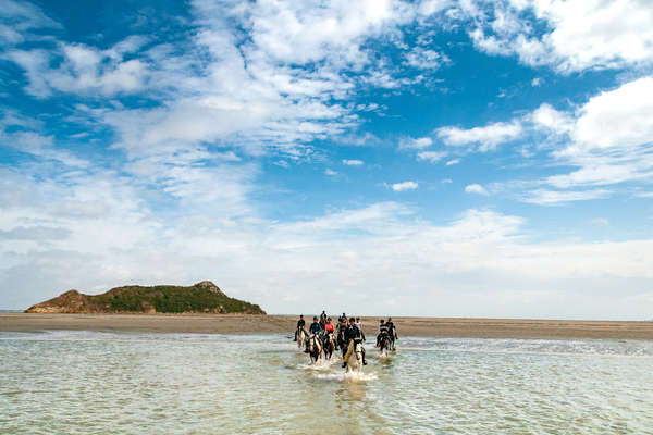 Horseback riders riding on a French beach