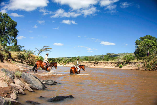 Horseback safari in the Maasai Mara: riders crossing a river