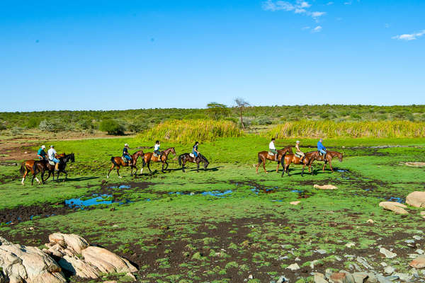 Multiple riders crossing a field in Kenya