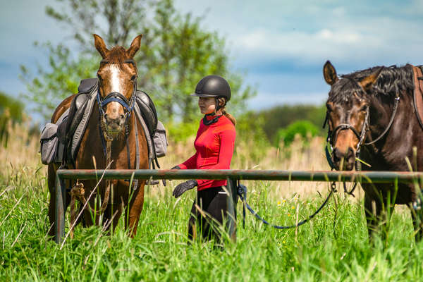 Rider standing by her horse during a trail ride in Poland