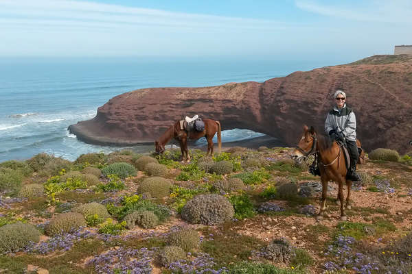 Rider standing with her horse in front of a view