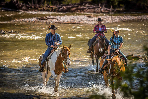Riders and horses riding out of a guest ranch in Canada