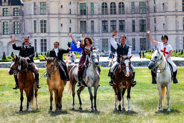 Riders in medieval costumes in front of a castle in the Loire Valley