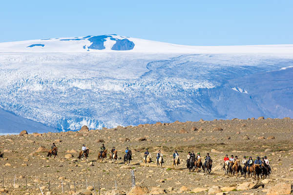 Riders on horseback in front of an Icelandic glacier