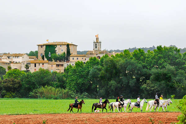 Riders passing a Spanish village on horseback