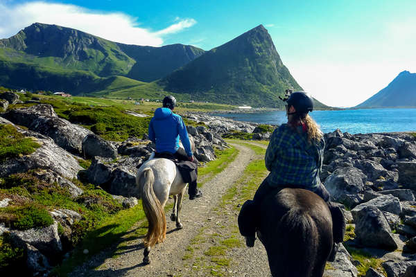 Riders riding in the Lofoten islands with a beautiful mountainous scenery