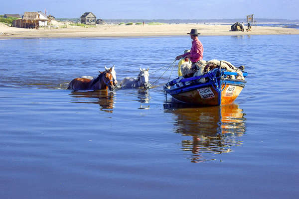 Two gauchos leading horses from a boat