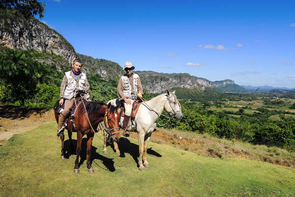 Two riders enjoying the view of the mountains in Cuba