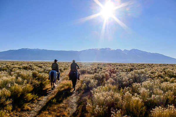 Two riders on horseback in Wyoming going towards the mountains