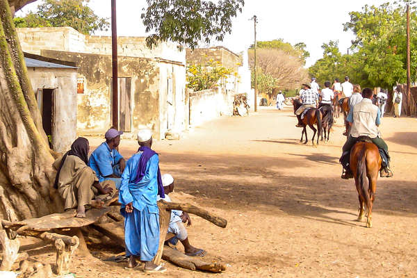 Villagers watching horses and riders ride away in Senegal