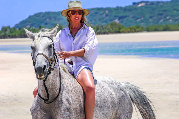 Woman riding a grey horse in a beach in Mozambique