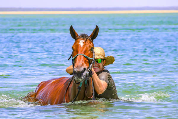 Woman swimming with a horse in Mozambique