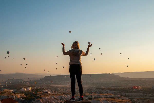 Woman with lots of hot air balloons in the background, in Cappadocia, Turkey